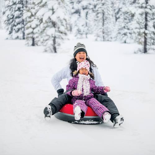 A mother and her child rides a sled in the snow in Flagstaff, AZ.